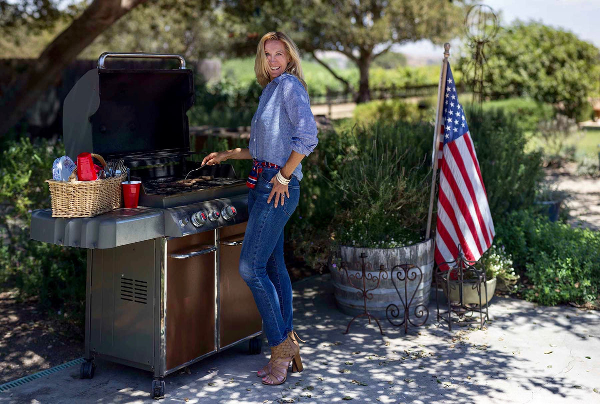 Santa Barbara California accessories designer and personal stylist, Paula Parisotto, wears jeans, a blue and white gingham button up, and tan heels while BBQing for Independence Day 