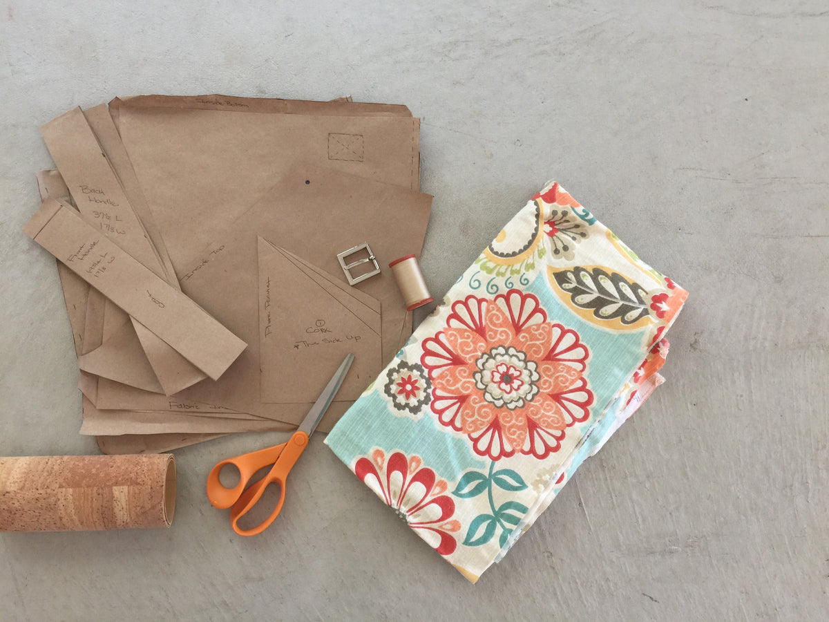 Paper purse pattern pieces, floral fabric and thread ready to be sewn into a cork purse