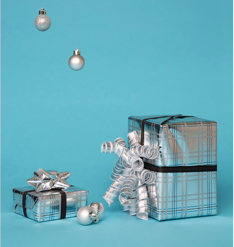 Two beautifully wrapped silver gifts sit in front of a Tiffany blue backdrop. Giving and receiving with gratitude for better money energy flow