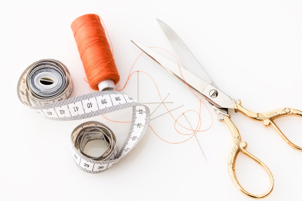 A tape measure, thread and scissors lay on a table ready to sew cork purses. 